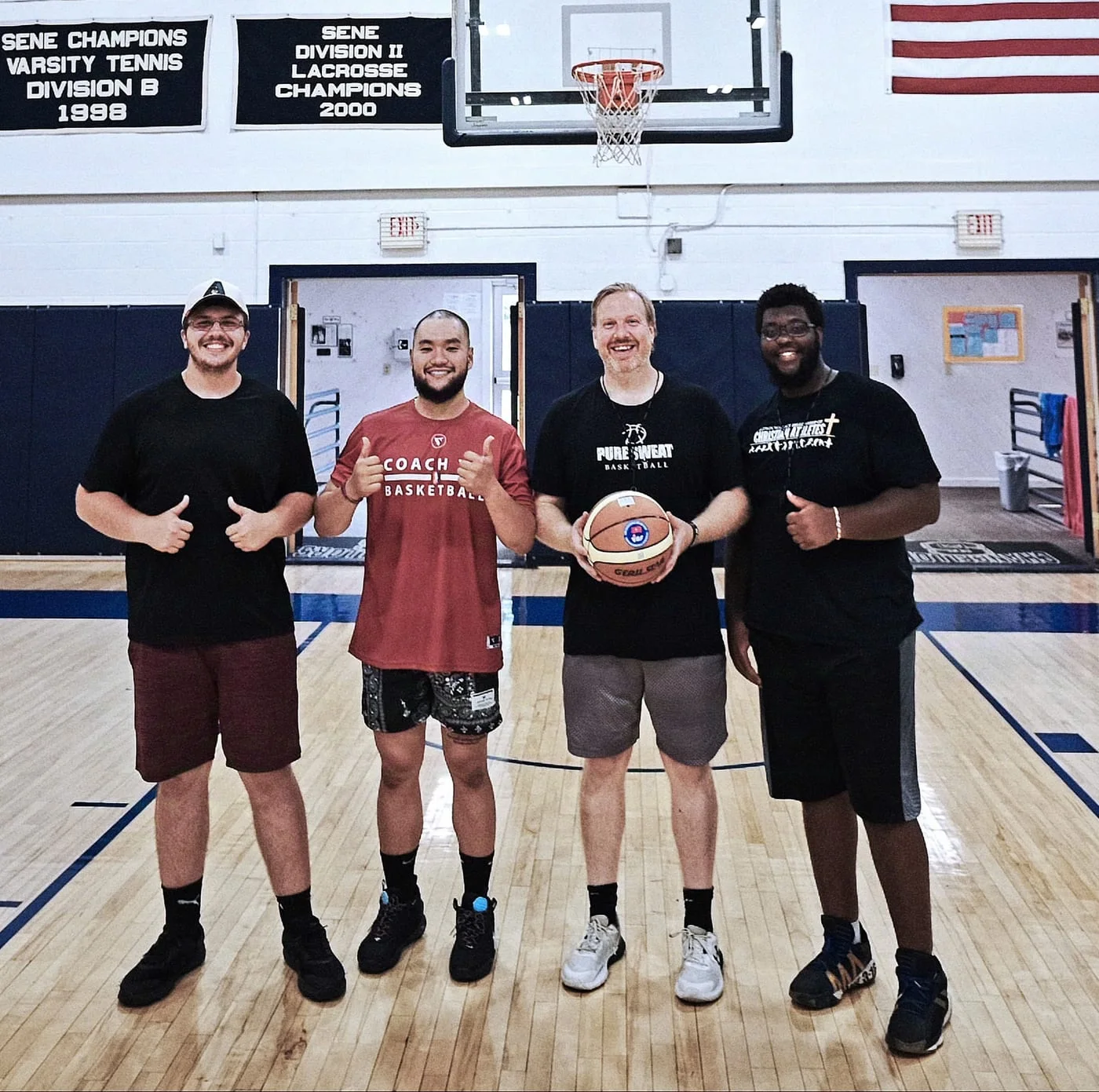 Coach Tin with three other basketball coaches at a gym in the United States.